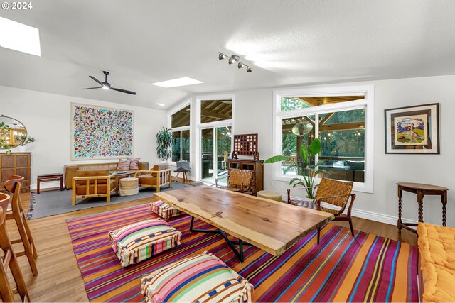 living room featuring a textured ceiling, ceiling fan, hardwood / wood-style floors, and lofted ceiling with skylight