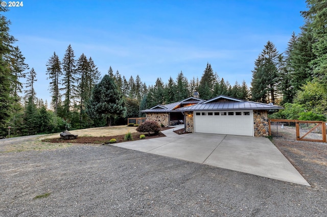 view of front of home featuring fence, driveway, a standing seam roof, stone siding, and metal roof