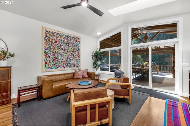 living room with ceiling fan, hardwood / wood-style floors, and lofted ceiling with skylight