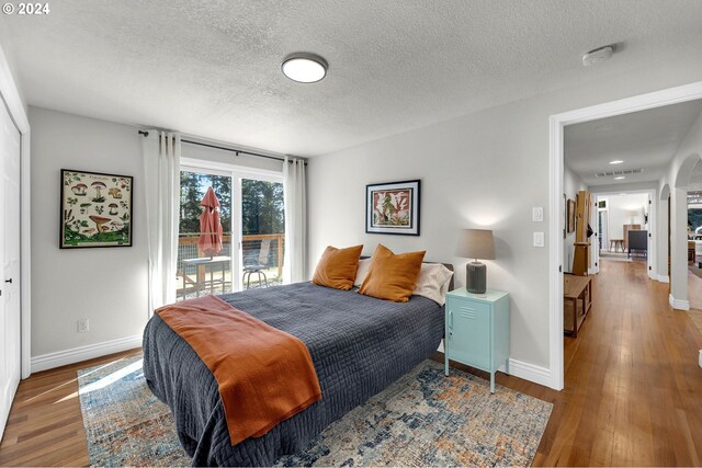 bedroom featuring a textured ceiling, access to exterior, a closet, and hardwood / wood-style flooring