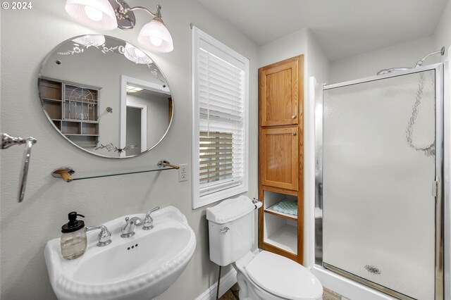 bathroom featuring toilet, sink, and an enclosed shower