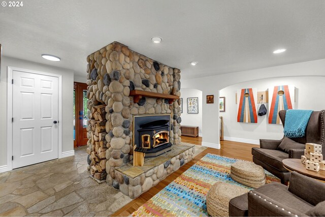 living room featuring a wood stove, a stone fireplace, and wood-type flooring