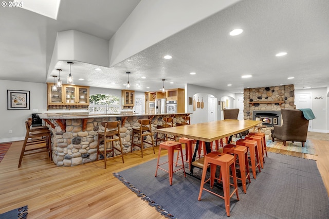 dining room with a fireplace, a textured ceiling, and light hardwood / wood-style flooring