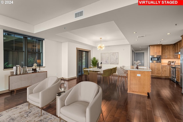 interior space featuring a notable chandelier, an island with sink, appliances with stainless steel finishes, and dark wood-type flooring