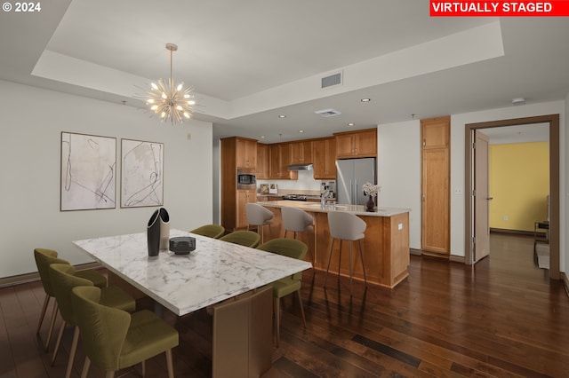 dining space featuring a tray ceiling, a chandelier, and dark wood-type flooring