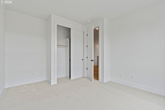 unfurnished bedroom featuring light carpet and a closet