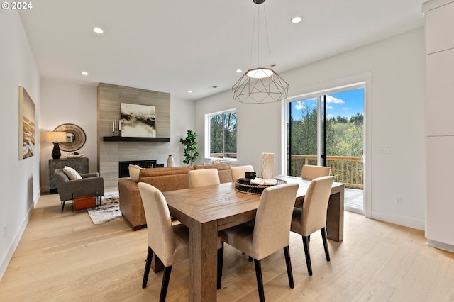 dining area featuring a large fireplace, light wood-type flooring, and a wealth of natural light