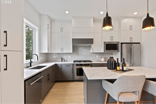 kitchen featuring decorative light fixtures, white cabinetry, appliances with stainless steel finishes, and sink