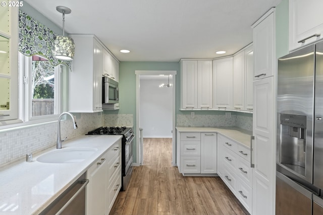 kitchen with white cabinetry, wood finished floors, appliances with stainless steel finishes, and a sink