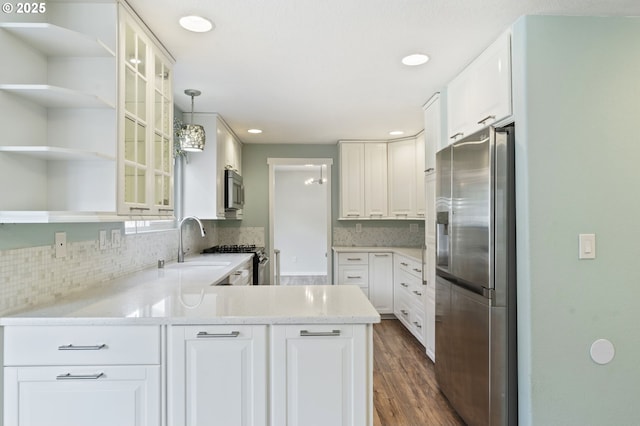 kitchen with backsplash, white cabinets, appliances with stainless steel finishes, and a peninsula