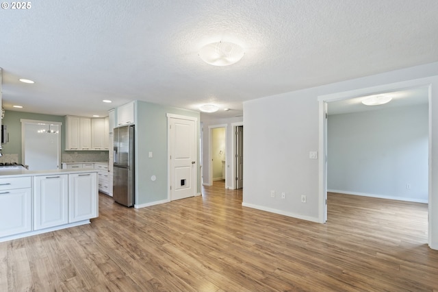 interior space featuring baseboards, light countertops, stainless steel fridge with ice dispenser, and light wood finished floors