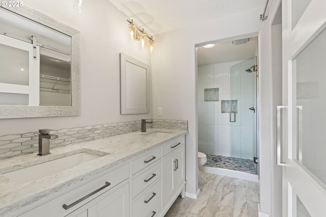 bathroom with a shower stall, toilet, and a sink