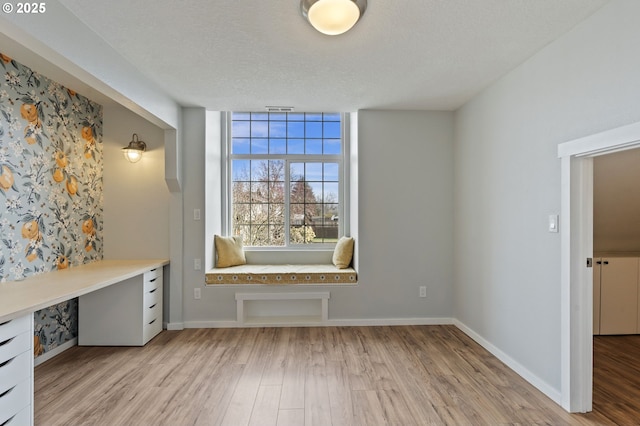 unfurnished office with visible vents, baseboards, a textured ceiling, and light wood-style flooring