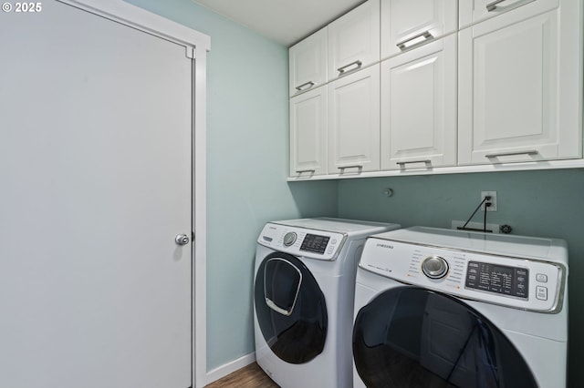 laundry area featuring washer and dryer, wood finished floors, cabinet space, and baseboards