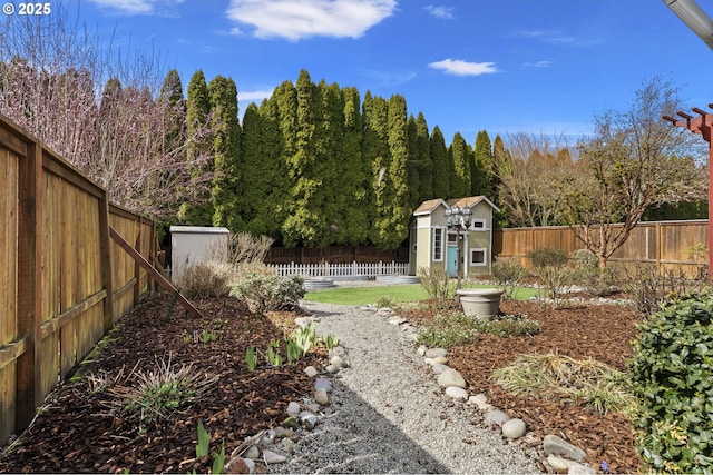 view of yard with an outdoor structure, a fenced backyard, a forest view, and a shed