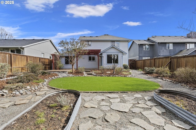 rear view of property featuring a yard and fence