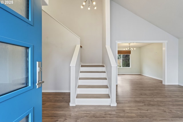 foyer featuring high vaulted ceiling, wood finished floors, baseboards, a chandelier, and stairs