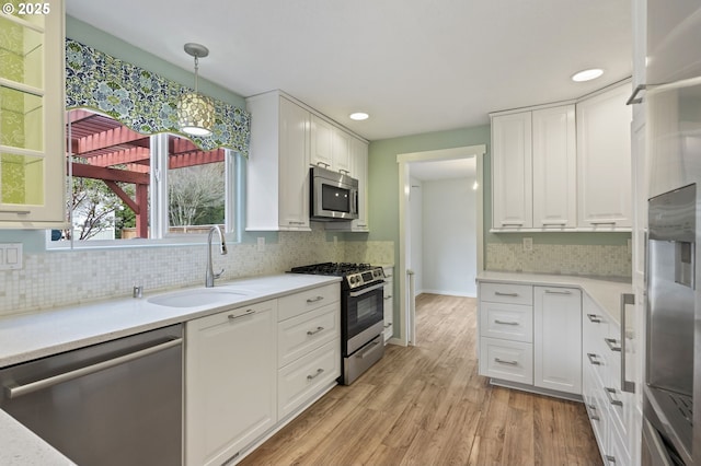 kitchen featuring light wood-style flooring, a sink, light countertops, white cabinets, and appliances with stainless steel finishes