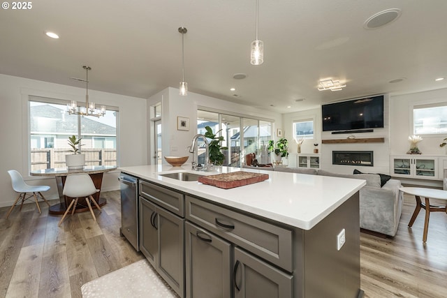 kitchen featuring pendant lighting, sink, a center island with sink, and light hardwood / wood-style flooring