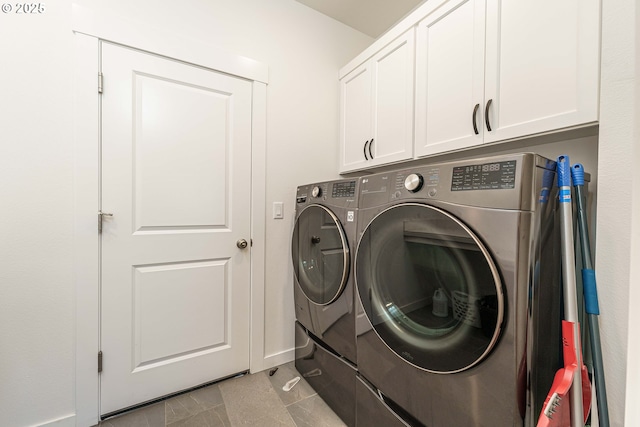 clothes washing area with cabinets, washing machine and clothes dryer, and light tile patterned flooring