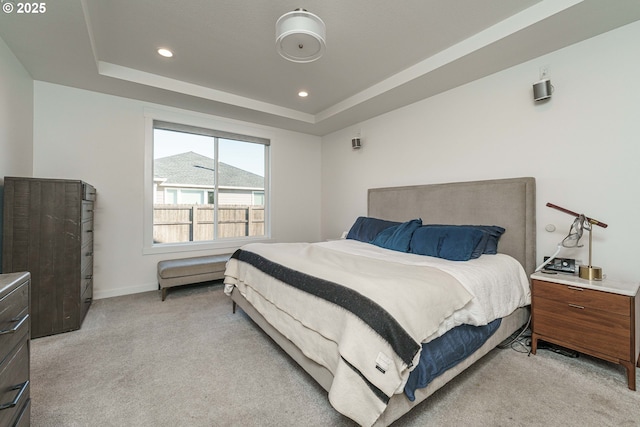 bedroom featuring light colored carpet and a tray ceiling