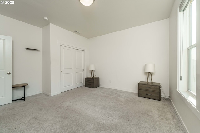 unfurnished bedroom with light carpet and a closet