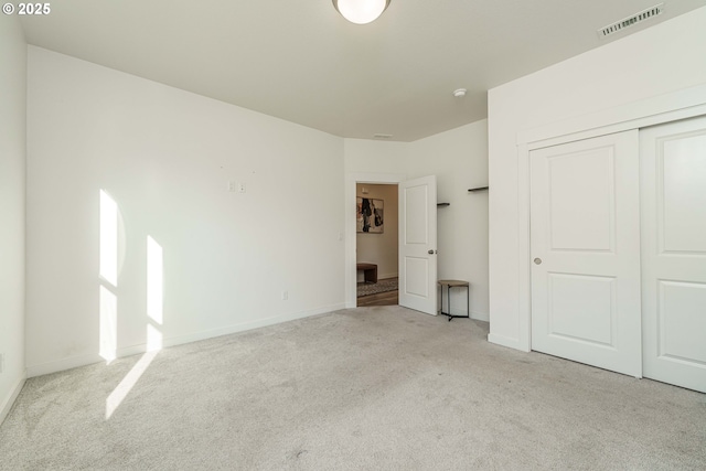 unfurnished bedroom with light colored carpet and a closet