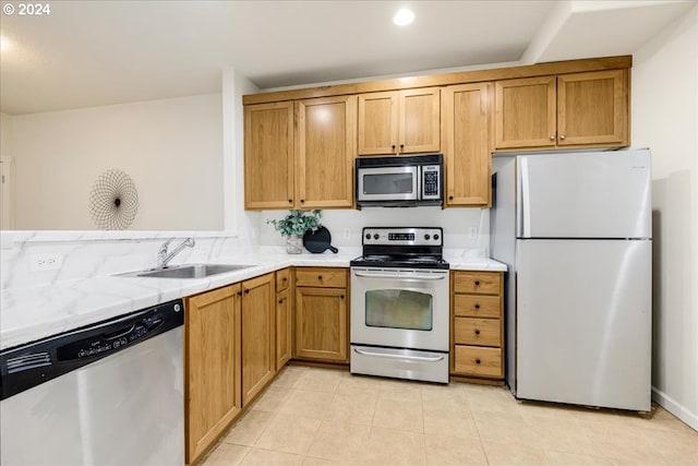 kitchen with light tile patterned floors, appliances with stainless steel finishes, brown cabinets, light countertops, and a sink