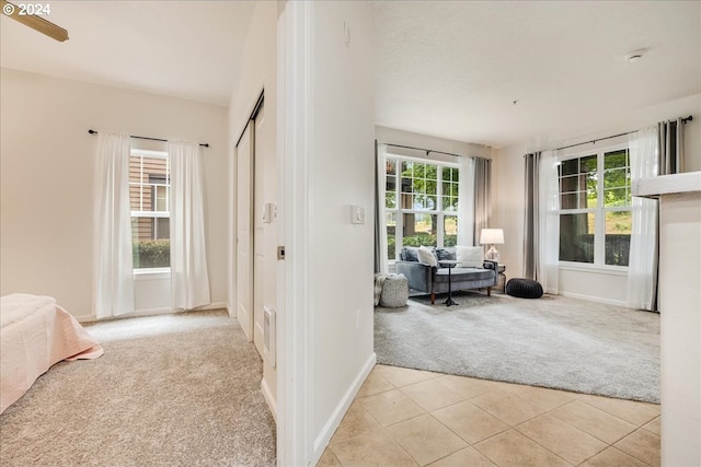 bedroom featuring light carpet, light tile patterned floors, and baseboards