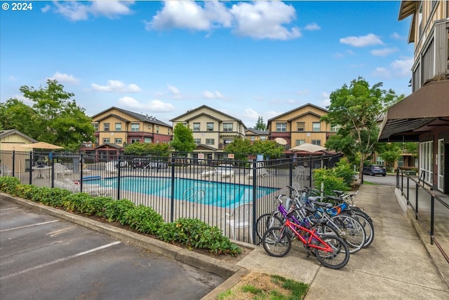 community pool featuring a patio area, fence, and a residential view