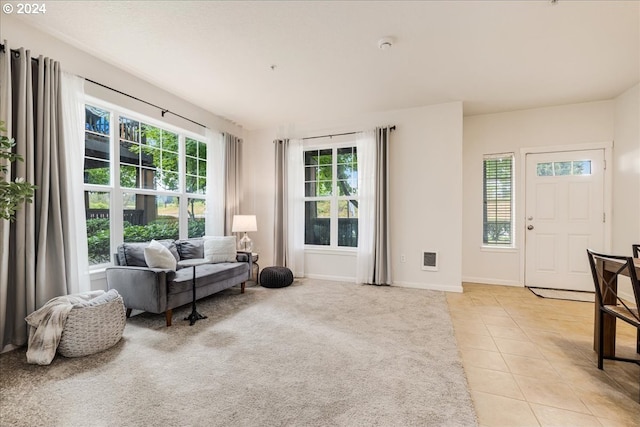 sitting room with baseboards, light tile patterned flooring, light carpet, and a healthy amount of sunlight