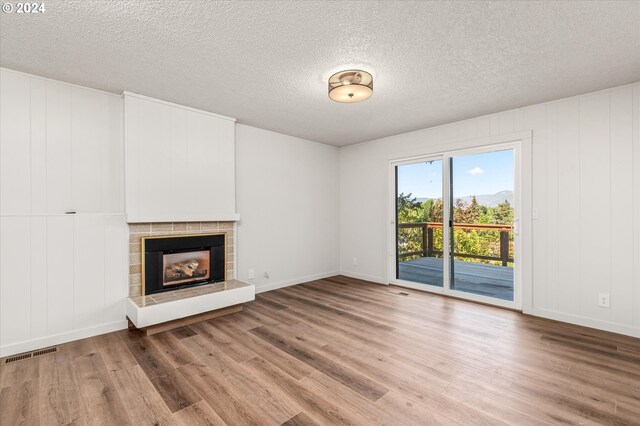 unfurnished living room with hardwood / wood-style floors, a fireplace, and a textured ceiling