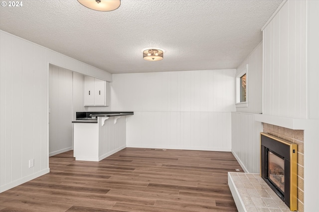 kitchen featuring dark hardwood / wood-style floors, white cabinetry, a breakfast bar area, kitchen peninsula, and a textured ceiling