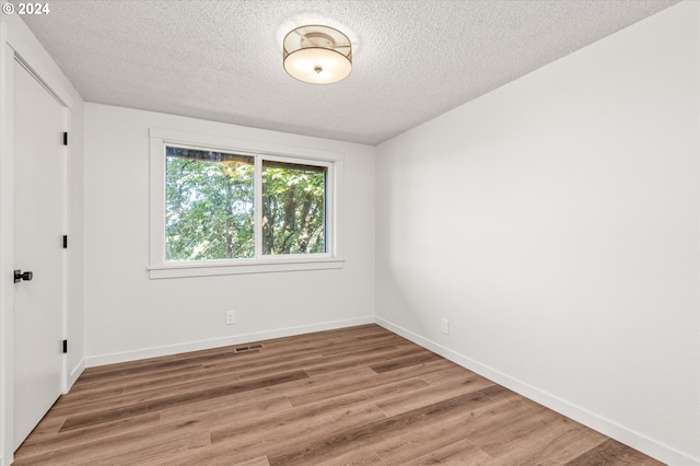 unfurnished room featuring hardwood / wood-style floors and a textured ceiling