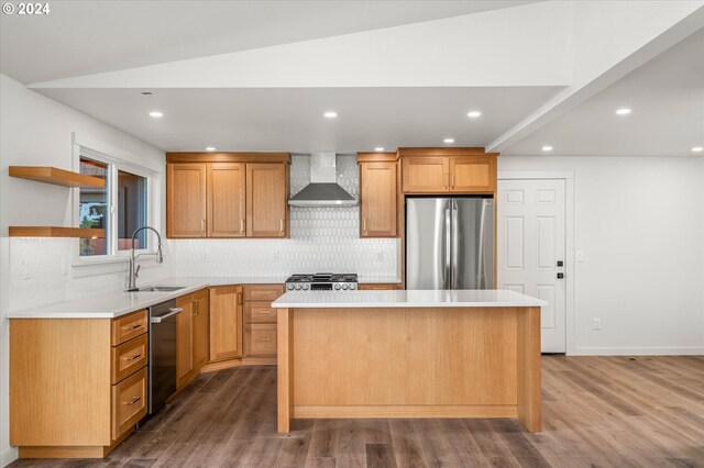 kitchen featuring wall chimney range hood, sink, a center island, and appliances with stainless steel finishes