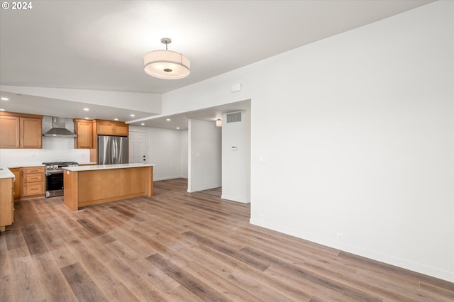 kitchen featuring wall chimney exhaust hood, tasteful backsplash, a center island, light hardwood / wood-style flooring, and stainless steel appliances