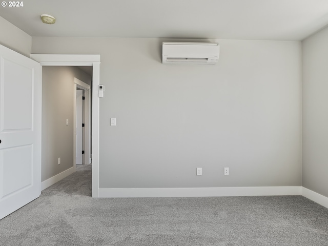 carpeted spare room with an AC wall unit and baseboards
