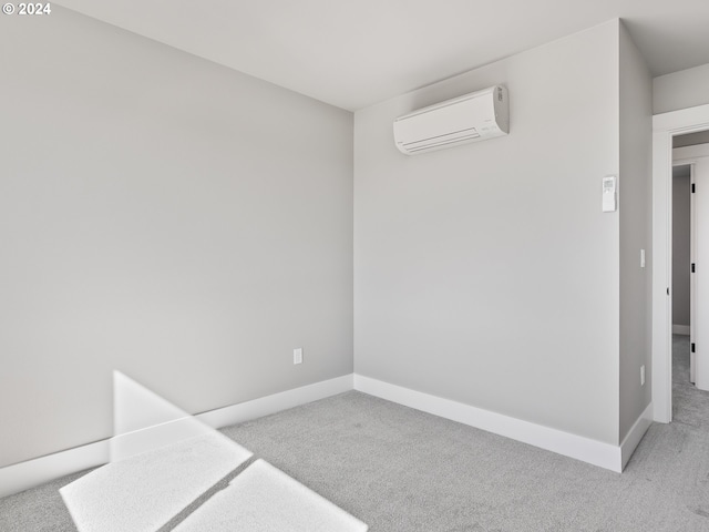 empty room featuring a wall unit AC, baseboards, and light colored carpet