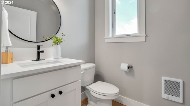 half bathroom featuring heating unit, baseboards, toilet, and vanity