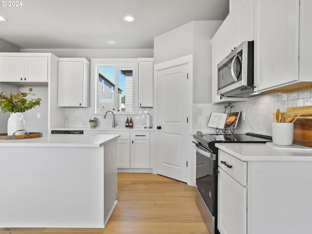 kitchen with a sink, white cabinetry, light countertops, and appliances with stainless steel finishes