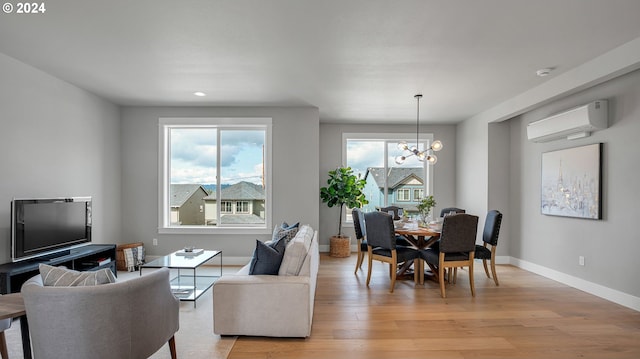 dining room with a notable chandelier, baseboards, a wall mounted air conditioner, and light wood-type flooring