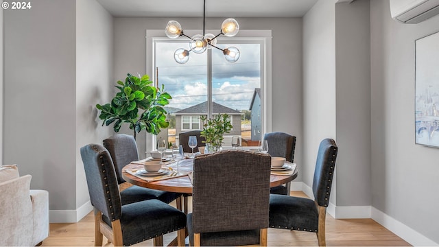 dining area featuring baseboards, light wood-type flooring, a wall mounted air conditioner, and an inviting chandelier