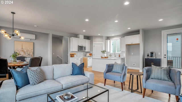 living area with light wood-style flooring, a notable chandelier, a wall mounted air conditioner, and recessed lighting
