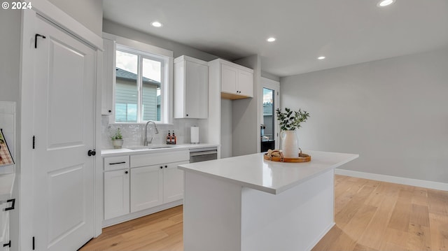 kitchen featuring light wood-type flooring, tasteful backsplash, a sink, and dishwasher
