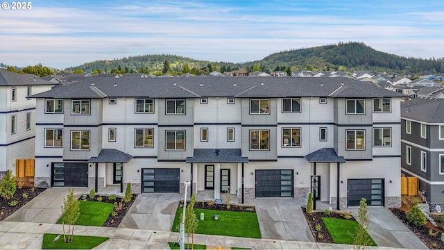 multi unit property featuring stone siding, driveway, a garage, and a mountain view