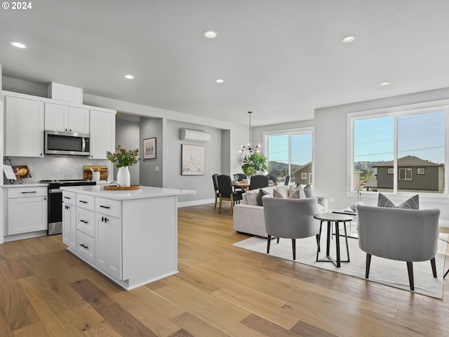 kitchen with decorative backsplash, appliances with stainless steel finishes, an AC wall unit, and light wood-type flooring