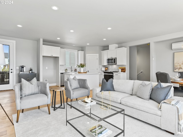 living area featuring a wall mounted AC, recessed lighting, and light wood finished floors