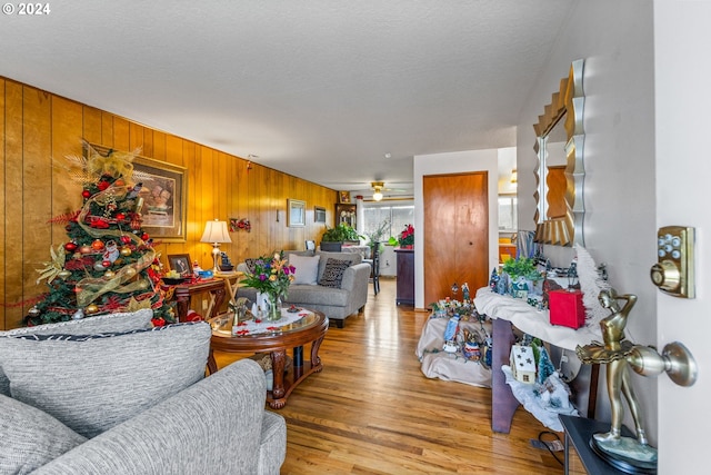 living room featuring wooden walls, a textured ceiling, and light hardwood / wood-style floors