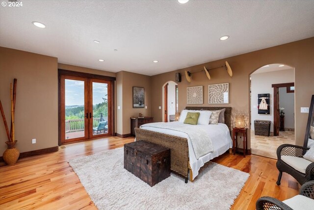 bedroom featuring french doors, a textured ceiling, light hardwood / wood-style flooring, and access to outside