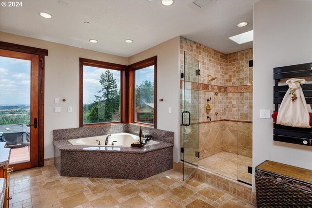 bathroom featuring a skylight and independent shower and bath